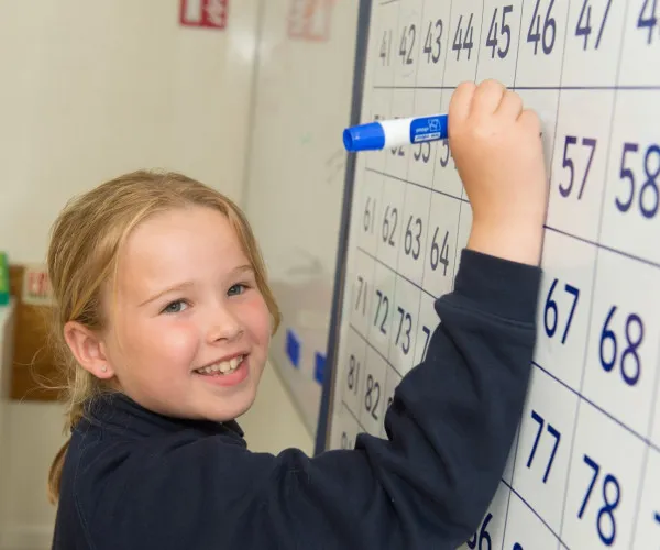 child writing on white board - CVP